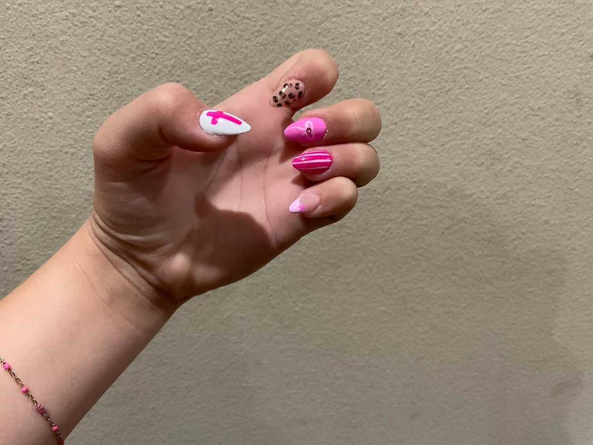 Close-up of hand with pink and purple nail art designs