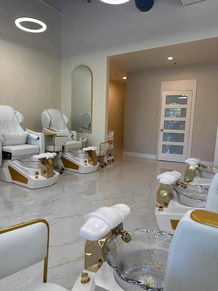 Modern nail salon interior with white pedicure chairs, marble flooring, gold accents